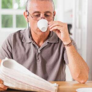 homem lendo jornal e bebendo cafe expresso